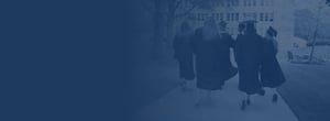 Students walking towards a building in graduation caps and gowns. 